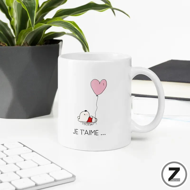White ceramic mug featuring a cartoon dog holding a pink heart-shaped balloon with the caption Je t'aime…
