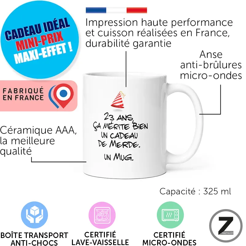 Mug blanc de 325 ml avec le texte: '23 ans ça mérite bien un cadeau de merde. Un mug.' et badges: fabriqué en France, lave‑vaisselle, micro‑ondes et anti‑brûlures (icônes).