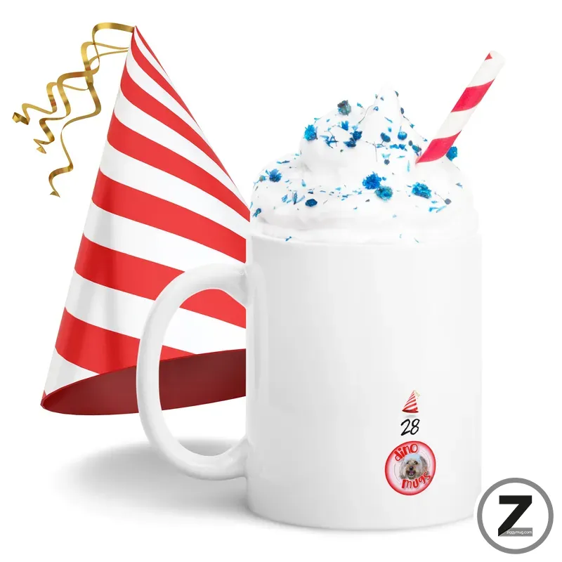 White mug topped with whipped cream and blue sprinkles, with a red striped party hat nearby and a striped straw for a festive celebration.