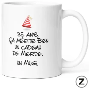 White mug with a red party hat and a French joke printed on it: '35 ans ça mérite bien un cadeau de merde. un mug.'