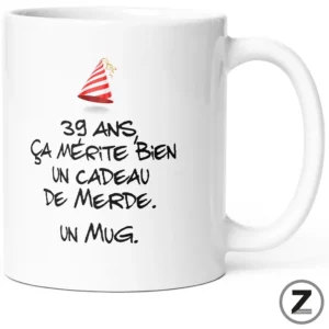White ceramic mug featuring a humorous French phrase in black handwritten font and a small red-and-white party hat graphic. The text reads: '39 ans, ça mérite bien un cadeau de merde. Un mug.'