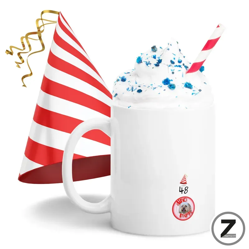 White mug topped with whipped cream and blue sprinkles, striped red-and-white straw, with a birthday party hat nearby.