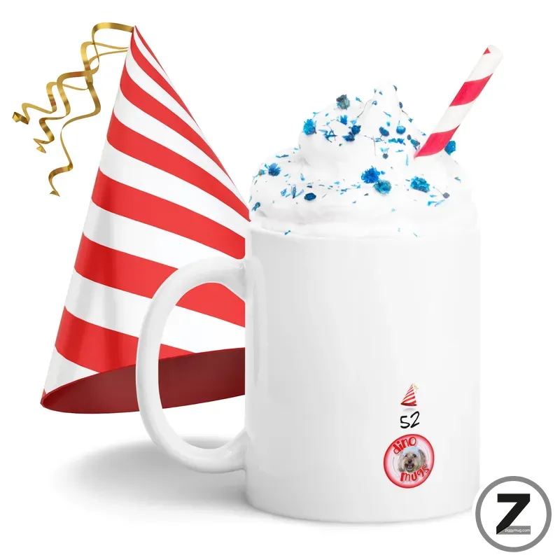 White mug with whipped cream topping and blue sprinkles, a red-and-white striped straw, and a striped party hat in the background.