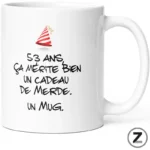 White mug featuring a playful party hat and bold French slogan: '53 ans ça mérite bien un cadeau de merde. Un mug.'