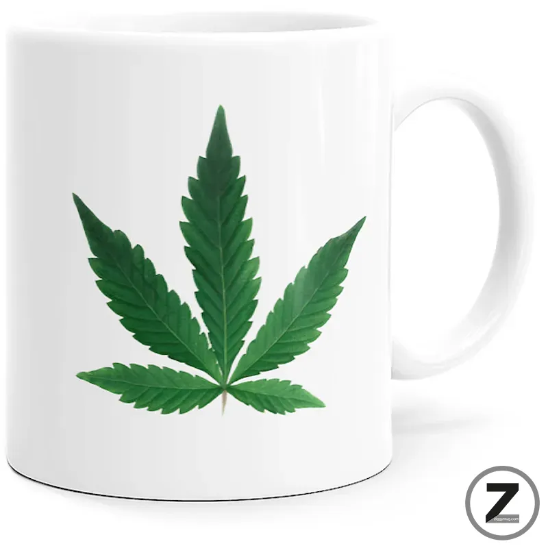 White mug featuring a large green cannabis leaf graphic on the side.