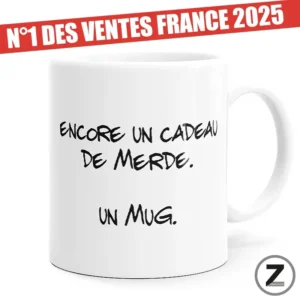 White mug with handwritten French text 'Encore un cadeau de merde. Un mug.' A red promo banner across the top reads 'N°1 DES VENTES FRANCE 2025'.