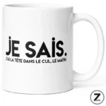 White ceramic mug with bold black text 'JE SAIS.' and a smaller French caption 'J'ai la tête dans le cul, le matin.'