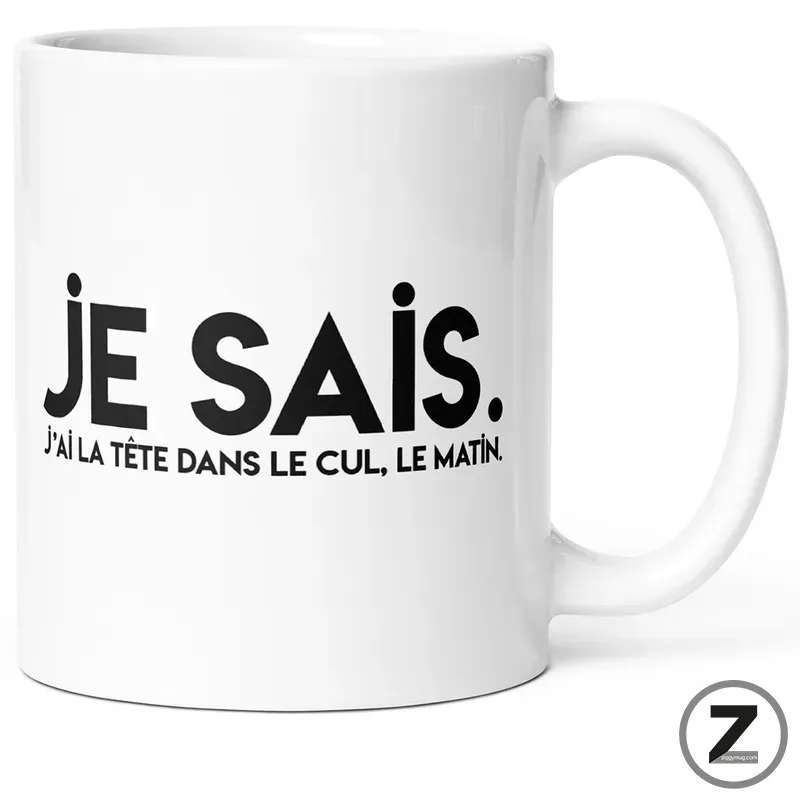 White ceramic mug with bold black text 'JE SAIS.' and a smaller French caption 'J'ai la tête dans le cul, le matin.'