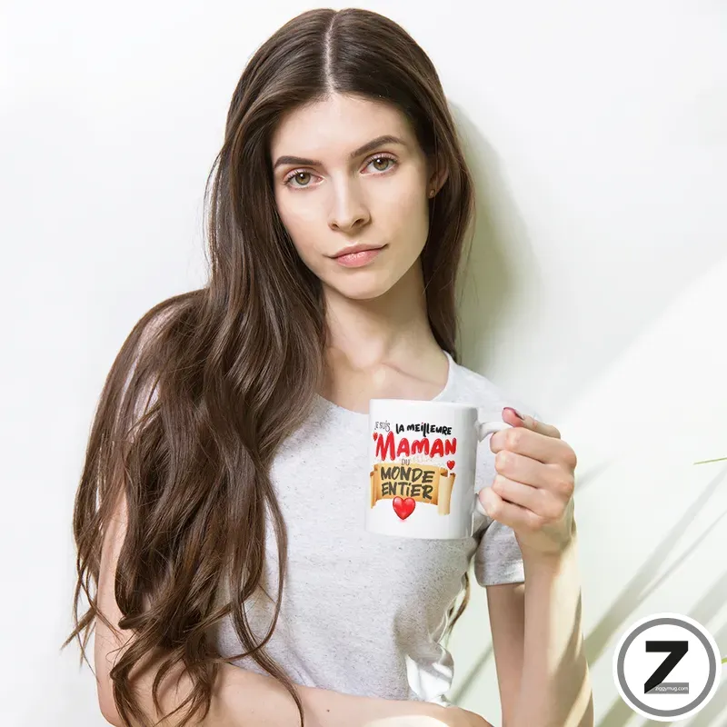 Young woman with long brown hair wearing a light gray t-shirt, holding a white mug with red and yellow text.