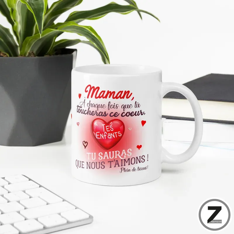 White mug with a red heart and French love message for mom on a clean desk beside a plant.