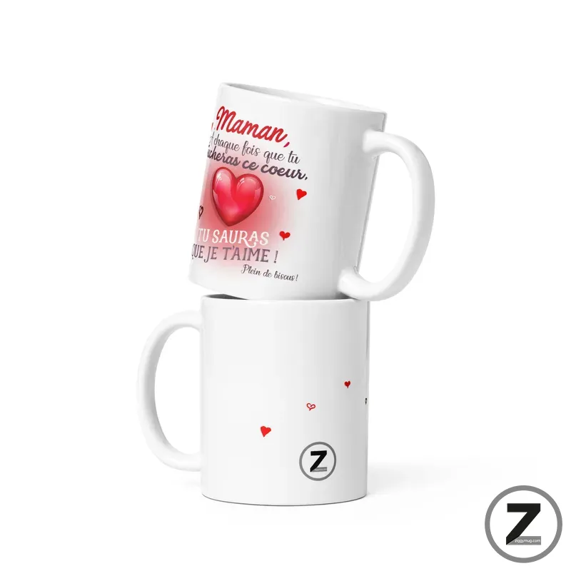 Two white ceramic mugs stacked, the top mug showing a red heart and French love text, the bottom mug plain with small hearts and a circular Z logo on the side.