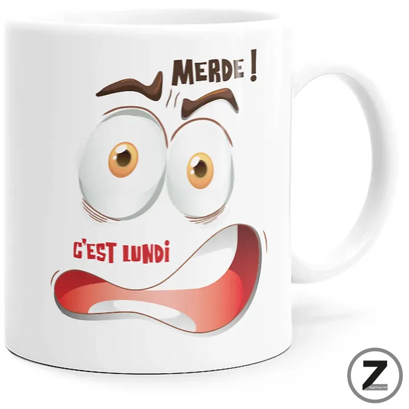 White mug featuring a shocked cartoon face with bulging eyes and a wide red mouth, plus the French text 'Merde! C'est lundi' for a Monday mood joke.
