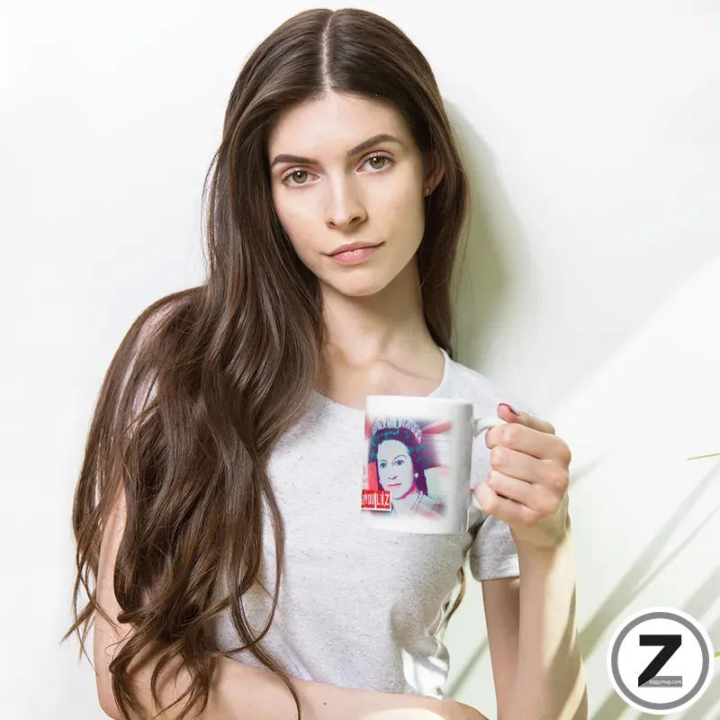 Woman with long brown hair wearing a light gray t-shirt, holding a white mug featuring a small image, against a pale background.