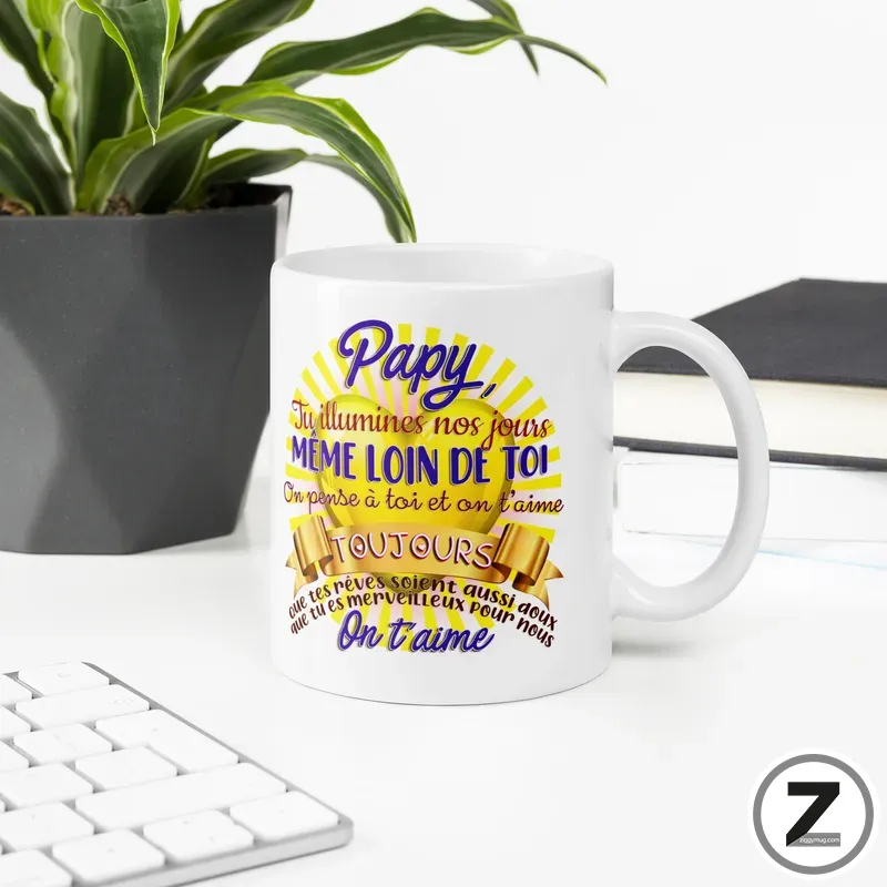 White ceramic mug on a clean desk featuring a colorful decorative inscription on a sunburst background, next to a plant and keyboard.