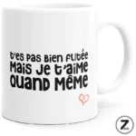White mug with bold black French phrase 't'es pas bien foutée mais je t'aime quand même' and a small pink heart.