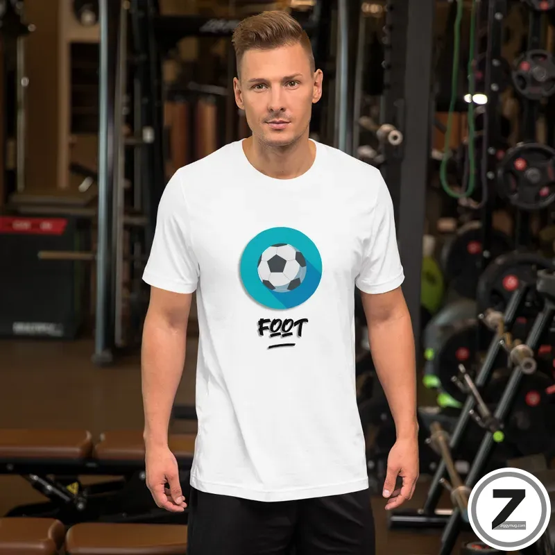 Man in a gym wearing a white T-shirt with a blue circle and soccer ball graphic and the word 'FOOT' beneath it.